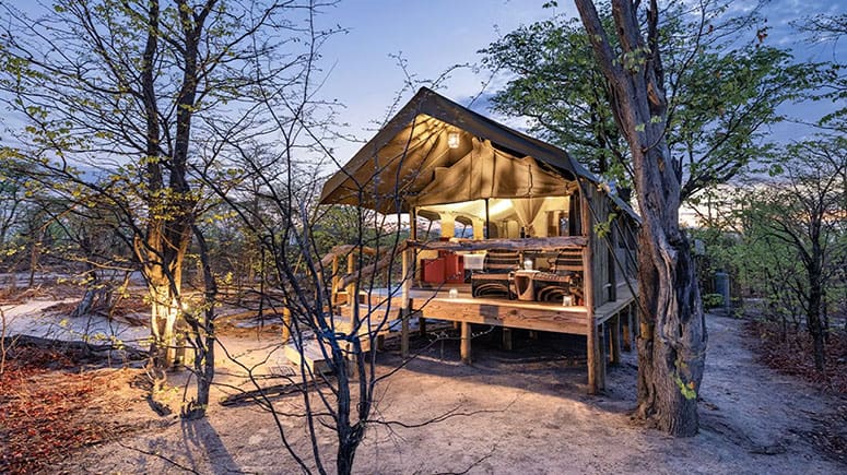Botswana safari camp at Elephant Pan overlooking a waterhole with elephants at sunset.