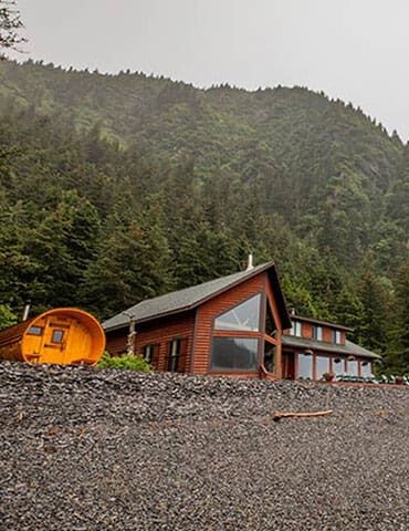 Ocean-view cabin at Kenai Fjords Wilderness Lodge overlooking Resurrection Bay, surrounded by spruce forest and glaciers.