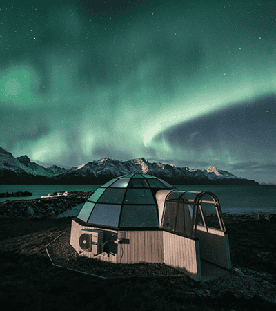 Igloo under northern lights and mountains