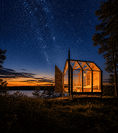 all glass cabin under starry skies in Sweden at nighttime<br />
